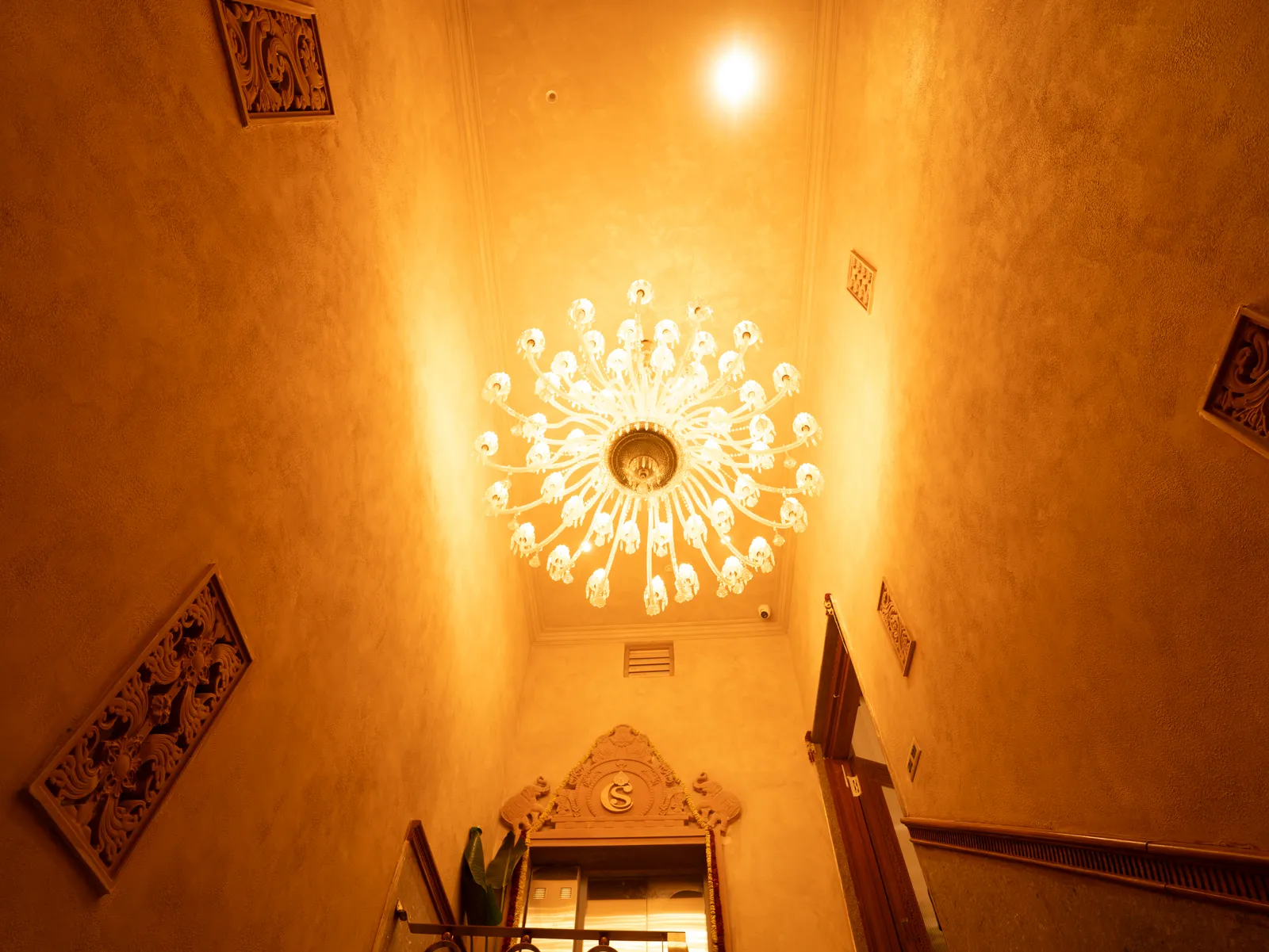 Stairwell with crystal chandelier and carved wall art — Chalukya Samrat